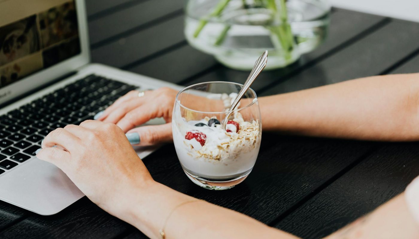 verre avec creme et cereales derriere ordinateur