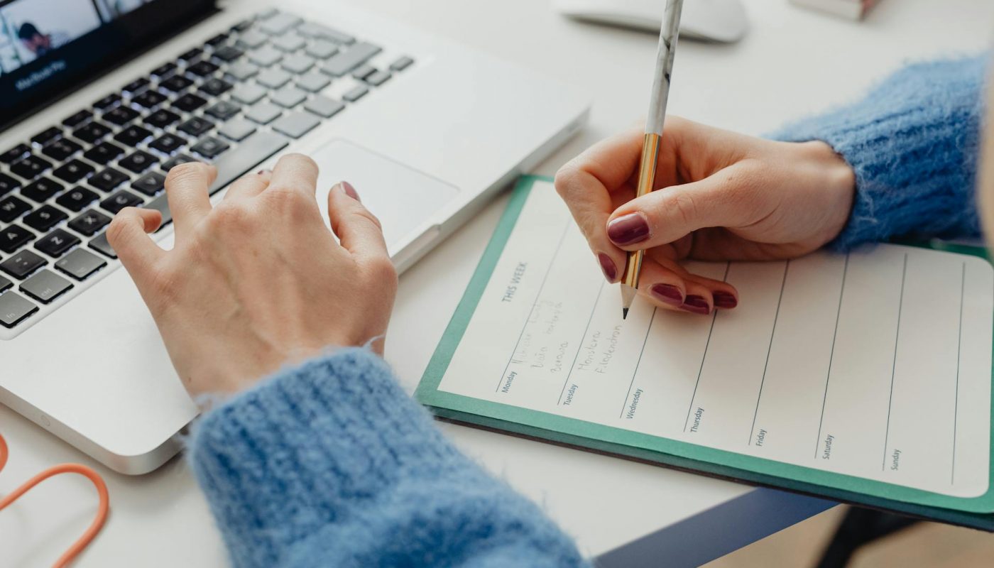 femme qui travail sur ordinateur et note son planner hebdomadaire